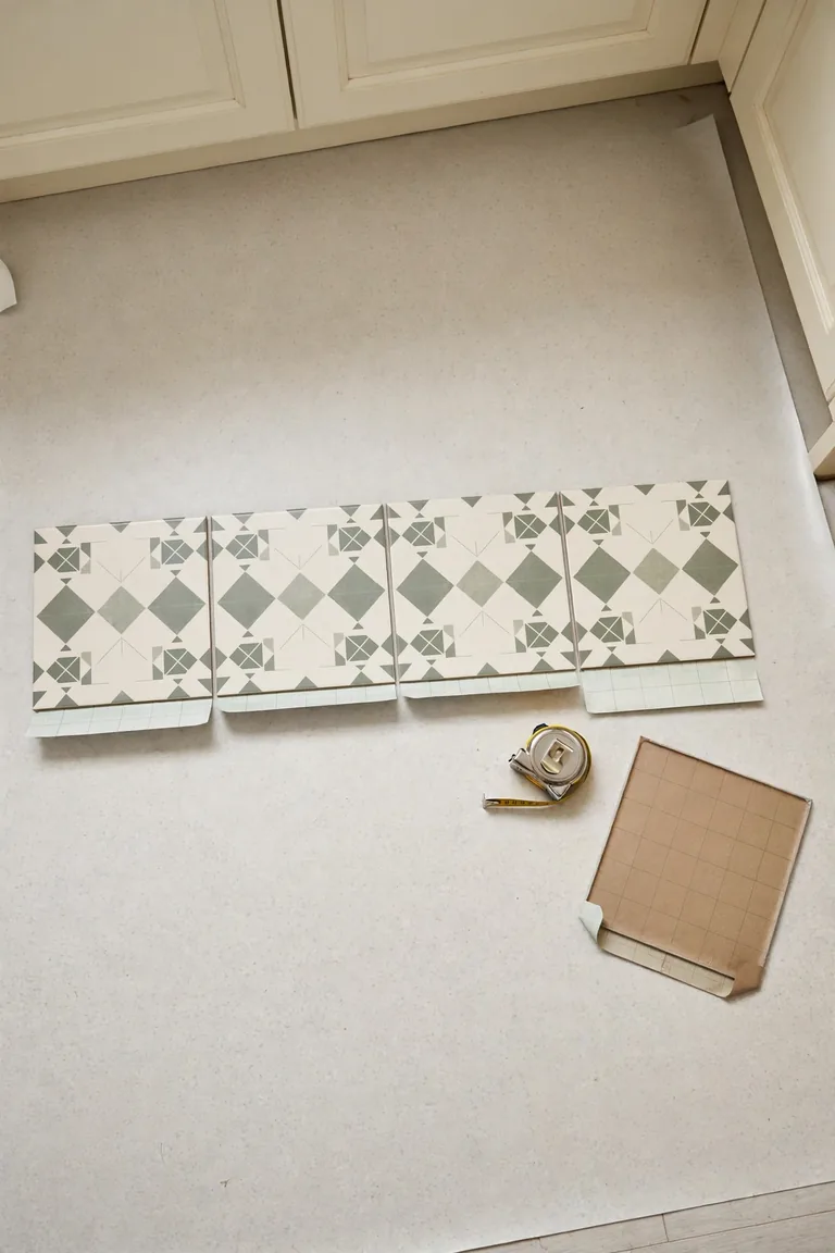 Peel and stick vinyl tiles arranged in a dry layout trial row on a kitchen floor before installation